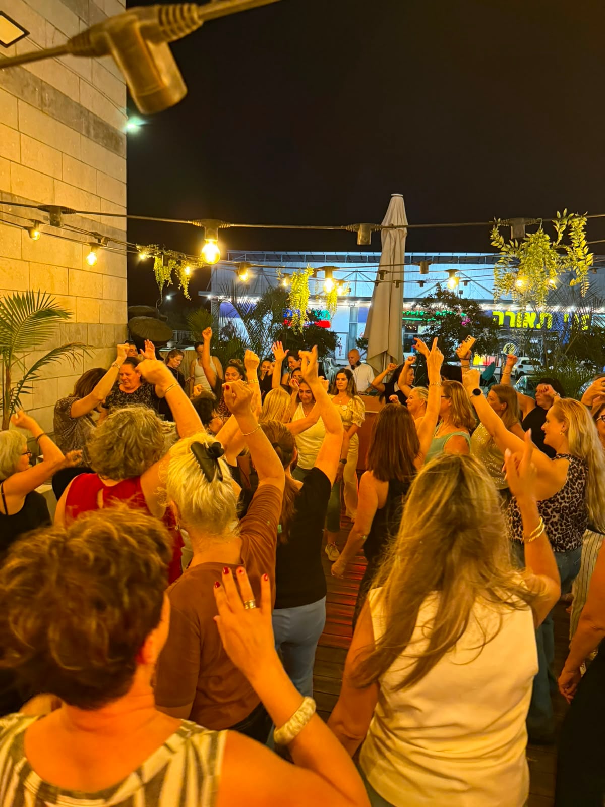 נשים רוקדות בצפיפות על הרחבה, ידיים באוויר